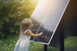 Little Child Standing by Solar Panel with Green Bokeh Background and Sun Rays