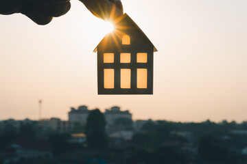 Wall Mural - House model in home insurance broker agent’s hand with building background. Real estate agent offer house, property insurance concepts.