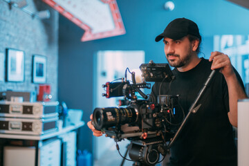 Wall Mural - Director of photography with a camera in his hands on the set. Professional videographer at work on filming a movie