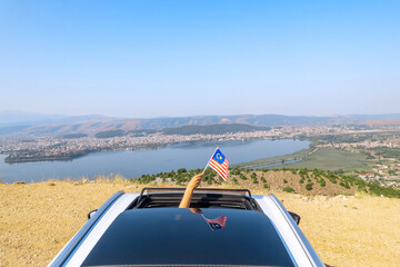 Wall Mural - Woman holding Malaysia flag from the open car sunroof,  window driving along the serpentine road in the mountains. Top view. Concept