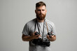 © Volodymyr - Professional bearded photographer holding a bunch of different vintage old cameras in a hands and on a shoulder.