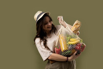 Wall Mural - Zero waste concept. Young beautifull brunette woman holding reusable mesh shopping bags with vegetables, products. Eco friendly mesh shopper. Zero waste, plastic free concept.