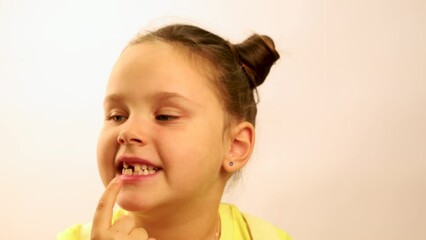 Wall Mural - Little funny girl wide smile, point finger at gap in mouth from fallen tooth and turning head closeup, white background. Joyful toothless child. Concept of healthy teeth and beautiful smile.