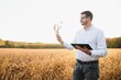 © Serhii - Portrait of farmer standing in soybean field examining crop at sunset.