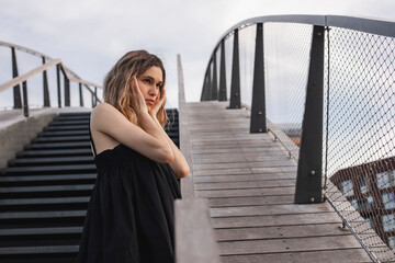 Close up depression blonde woman with two thin braids standing on the stairs. Depression, sadness, problem concept. Unhappy upset woman touching temples, suffering from strong tension headache.