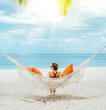 © Soloviova Liudmyla - Young woman relaxing in wicker hammock on the sandy beach on Mauritius coast and enjoying wide ocean view waves. Exotic countries vacation and mental health concept image.