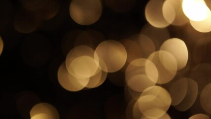 Wall Mural - Gold Sepia Bokeh Shimmering On Black. Abstract overflow movement of defocused circles in sepia tones. Circle Bokeh Lights smooth fading. Light Leaks 4K moving background. 