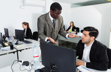 Wall Mural - Outraged serious African American businessman expressing dissatisfaction with work of frustrated man in coworking space