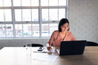 © Wavebreak Media - Happy asian businesswoman sitting at desk and using laptop, working late at office