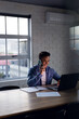 © Wavebreak Media - Happy biracial businessman using laptop, talking on smartphone, working late at office, copy space