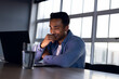 © Wavebreak Media - Happy biracial businessman sitting at desk and using laptop, working late at office
