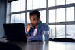 © Wavebreak Media - Biracial businessman sitting at desk and using laptop, working late at office, copy space
