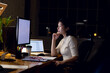 © Wavebreak Media - Asian businesswoman standing at desk, using computer with copy space, working late at office