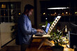 © Wavebreak Media - Biracial businessman standing at desk, using laptop, working late at office