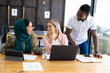 © Wavebreak Media - Busy casual diverse business people discussing work and using laptop in modern office