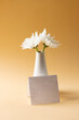 Image of white flowers in white vase and card with copy space on yellow background