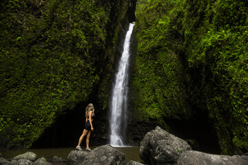 Girl hiker in front of waterfall in hawaii green jungle forest. 