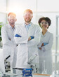 © ASDF - Smiling scientists looking at camera arms crossed in laboratory