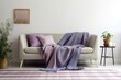 © The 2R Artificiality - Mockup of a living room interior with a blue sofa and a purple throw blanket against a blank white wall. Room Lighting is an example. Generative AI