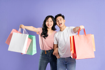 Sticker - image of asian couple holding shopping bags on purple background