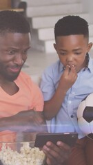 Poster - Animation of lights over happy african american father and son watching soccer match on smartphone