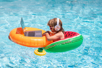 Wall Mural - Freelance work, distance online work, e-learning. Summer business. Kid remote working on laptop in pool. Little business man working online on laptop in summer swimming pool water.