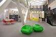 © Mint Images - A healthcare college library with open spaces, green chairs and book stacks. A modern light and airy building.
