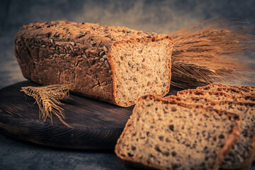 Freshly baked bread and wheat ears on rustic background. Toned.