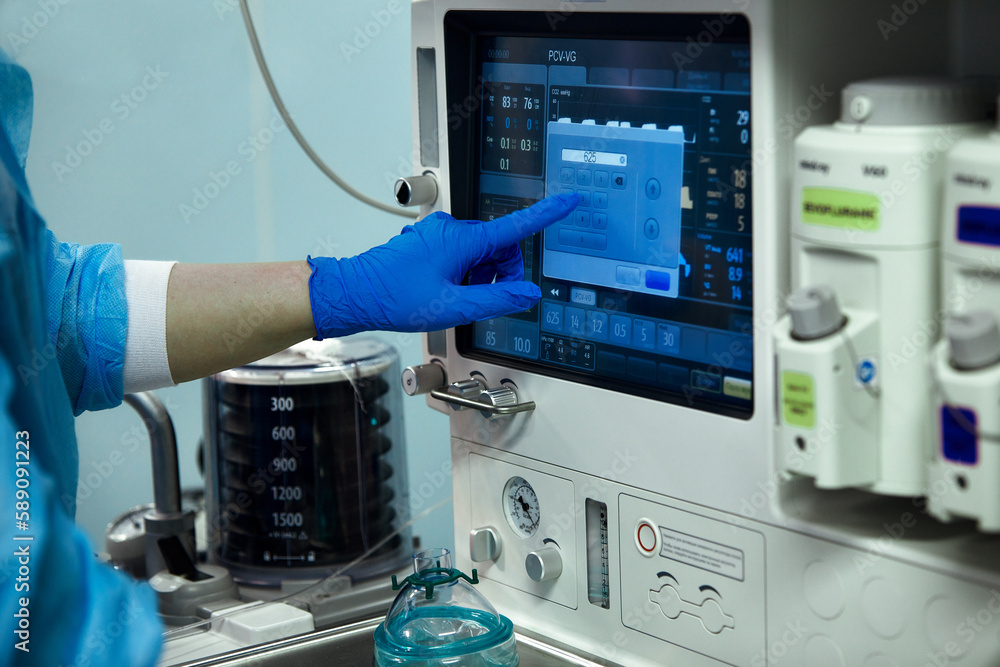 The doctor's hand operates a heart rate monitor in a hospital theater. Medical device for monitoring vital signs in a hospital on an anesthesia surgery monitor. ECG patient monitor. medical