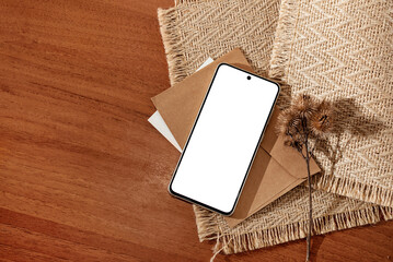 Wall Mural - Mobile phone screen mockup, minimalist aesthetic business template with smartphone, crafted envelope and dried flowers on brown table background, copy space