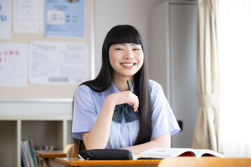 Wall Mural - High school girls studying in a classroom, looking at the camera, short sleeves, with space for photocopying