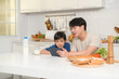 © tonefotografia - Young Asian father and his son using digital tablet enjoying together in kitchen at home