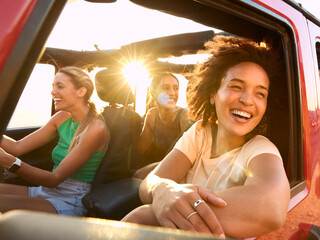 Wall Mural - Group Of Laughing Female Friends Having Fun In Open Top Car On Road Trip