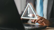 © Montri - Businessman using computer laptop with triangle caution warning sing for notification error and maintenance concept..