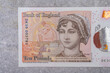 Banknotes in denominations of 10 with the image of a portrait of Jane Austen on a gray background