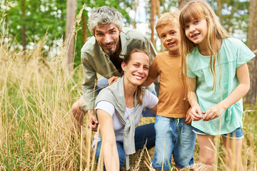 Wall Mural - Happy family exploring together in forest during vacation