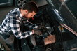 © standret - Using the tool and fixing the car. Man in uniform is working in the auto salon