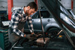 © standret - Black car is repairing. Hood is opened. Man in uniform is working in the auto salon