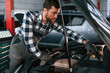 © standret - Focused on work. Repairing the car. Man in uniform is in the auto salon