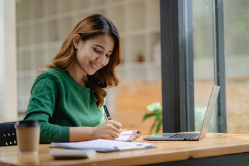 young woman working in a cafe using laptop and drinking coffee asian female student using a computer