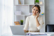 © ArLawKa - Serious asian businesswoman using customer service phone sitting at table, sales manager focused woman on mobile business phone discussing work with customer in office