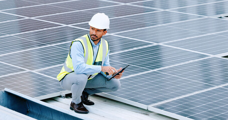 Canvas Print - Young engineer or contractor inspecting solar panels on a roof in the city. One confident young manager or maintenance worker smiling while installing power generation equipment and holding a tablet