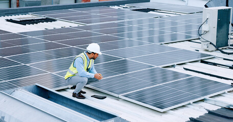 Engineer or contractor measuring solar panels on a roof of a building. Engineering technician or electrician installing alternative clean energy equipment and holding a tablet to record measurements