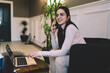 © BullRun - Smiling woman talking on smartphone while sitting on sofa
