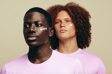 Wall Mural - Two young men with unique skin tones use beauty cream on their faces