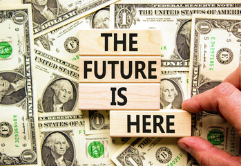 Wall Mural - The future is here symbol. Concept words The future is here on wooden block. Beautiful background from dollar bills. Businessman hand. Motivational business the future is here concept. Copy space.
