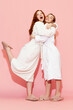 © master1305 - Full-length image of pretty young girls, friends in white bathrobes posing against pink studio background. Relaxation. Concept of youth, face care, beauty, friendship, party, spa, cosmetics