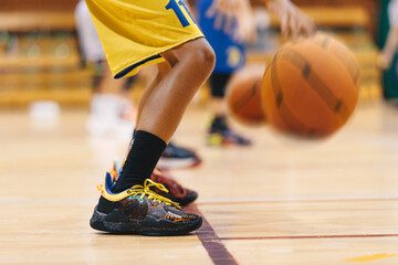 Wall Mural - Junior level basketball players bouncing basketball ball in line. Young basketball players with classic ball at school court. Basketball training session for youth. School sports class