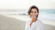 © Robert MEYNER - Happy 40 year old woman on the beach smiling with serenity. Generative AI