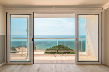 Picturesque view from a guest house through panoramic window with terrace to the sea on a sunny warm summer day with blue skies in a luxury resort. Concept of a room in a five-star hotel